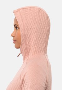 Felpa con cappuccio rosa chiaro in tessuto testurizzato con motivo a diamante. Presenta una chiusura con zip al collo e dettagli a costine lungo le cuciture.