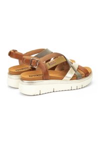 Sandalias de tiras cruzadas en marrón y dorado con plantilla acolchada, una suela blanca ligera y un detalle metálico plateado en el talón.