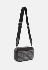 Borsa a tracolla nera con forma rettangolare, caratterizzata da una stampa del logo su un lato, materiale testurizzato e una tracolla regolabile.
