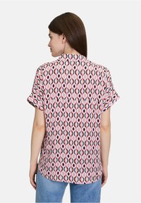 Blusa a maniche corte con un motivo a onde rosa, rosso e nero, realizzata in tessuto leggero, con un parte posteriore a yoke e una texture morbida.