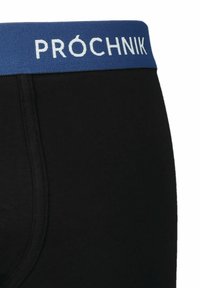 Czarne bawełniane bokserki z niebieskim elastycznym paskiem, na którym znajduje się napis "PRÓCHNIK" w białym kolorze. Gładka tekstura z detalami przeszyć.