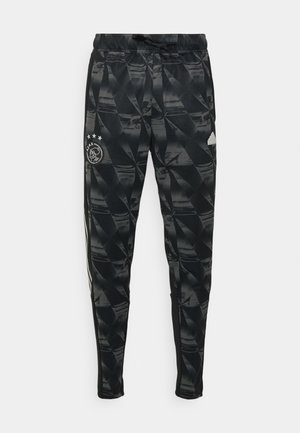 Schwarze Sporthose mit geometrischem Muster, elastischem Bund und seitlichen Streifen. Mit Ajax-Logo und drei Sternen auf dem linken Oberschenkel.