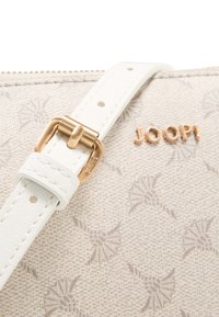 White handbag with a textured fabric featuring a subtle pattern. Gold hardware accentuates the design, with a logo reading "JOOP!" prominently displayed.