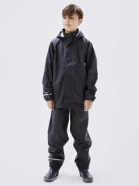 Zwarte waterdichte jas en broek met elastische manchetten, gemaakt van soepel materiaal. Bevat een capuchon en eenvoudige zilveren accenten.