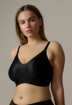 Zwarte geribbelde bralette met een V-vormige halslijn, dunne verstelbare bandjes en een aansluitend ontwerp dat zich naar het lichaam vormt.
