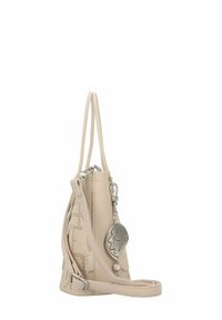 Beige Lederhandtasche mit durchbrochenem Design, Reißverschluss, abnehmbarer Schulterriemen und silberner Hardware. Mit einem dekorativen Anhänger an der Seite.