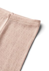 Lichtroze textiel met structuur, voorzien van een subtiel patroon en een elastische tailleband, gedeeltelijk opgevouwen om het zachte, gebreide materiaal te tonen.