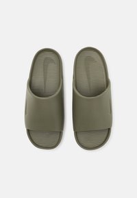 Olive spalvų skaidrūs šlepetės su tekstūruotais pado paviršiais ir subtiliais „Nike“ logotipais ant dirželių, rodoma iš viršaus ant baltos fono.