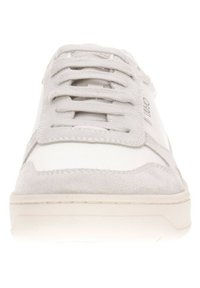 Baskets blanches avec des accents en daim gris, lacets plats, embout arrondi et semelle en caoutchouc texturé ; logo sur le côté et design minimaliste.