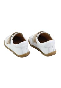 Zapatos blancos con parte superior de cuero suave, correas en beige que contrastan, punta redonda y suela de goma flexible. Dos cierres de Velcro en la parte posterior.