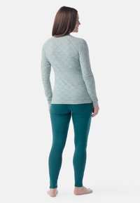 Light green long-sleeve top with a floral pattern and teal leggings. The top features raglan sleeves and a fitted silhouette.