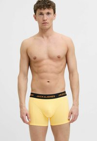 Sárga pamut boxer alsónadrág fekete derékpánttal, amelyen a "JACK & JONES" logó található. A dizájn illeszkedő szabású, varrat nélküli elülső résszel.