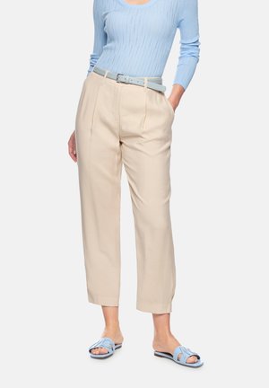 Woman wearing beige high-waist pants, light blue belt, light blue long-sleeve ribbed top, and light blue open-toe flat sandals.