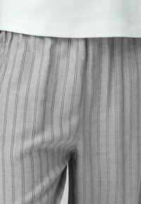 Grå randiga byxor med tvåtoniga smala ränder, gjorda av ett lätt tyg med en mjuk struktur och avslappnad passform.