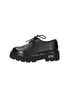 Scarpa nera in pelle con lacci, suola spessa scanalata e targhetta metallica sul lato con la scritta "CULT" su sfondo bianco.