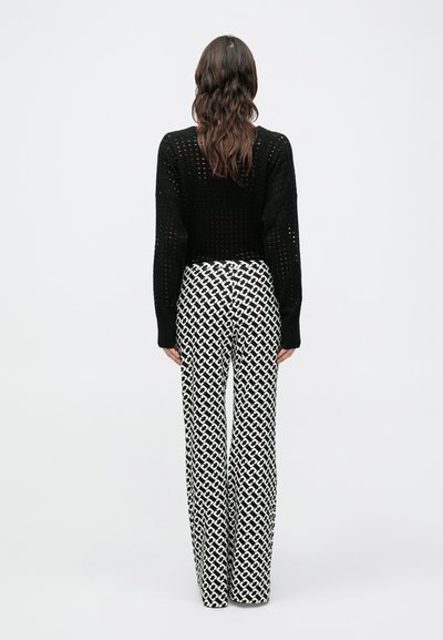 Mustast kudumist, pika varrukaga otsene pealmine osa; kõrge vöökohaga, laia jalaga püksid, millel on valge geomeetriline muster.