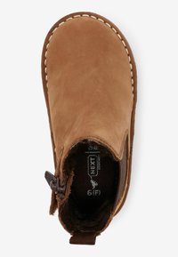 Bottines en daim marron avec un bout arrondi, des coutures contrastantes et une fermeture éclair sur le côté. Doublure intérieure douce visible.