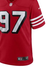 Maillot NFL rouge avec de grands numéros noirs "97", des rayures blanches sur les manches, le logo Nike et une étiquette inférieure indiquant la taille médium.