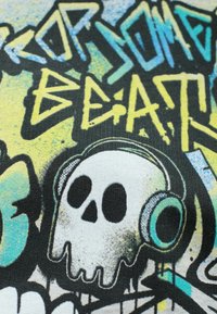 Czarny materiał zdobiony żywą sztuką graffiti z niebieskimi i żółtymi plamami. Na wzorze wyraźnie widoczna jest czaszka nosząca słuchawki.