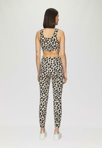 Leopardenmuster Leggings und passendes Crop-Top, aus dehnbarem Stoff. Hat ein tailliertes Design und breite Träger, in Beige und Schwarz.