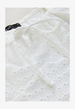 Valge struktureeritud kangas, millel on tikitud mustrid ja sidumisdetail kaeluses. Sobib igapäevaseks kandmiseks. Märgitud "NEXT."