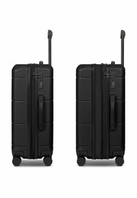 Valigia rigida nera con finitura testurizzata, doppie ruote, manico telescopico e serratura a combinazione. Dotata di maniglie superiore e laterale.