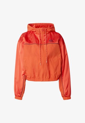 Jasně oranžová větrovka s kapucí, předním zipem, šňůrkami, elastickými manžetami, bočními kapsami a malým logem na hrudi.