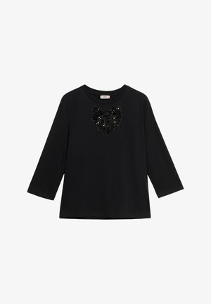 Camisa negra de manga larga con cuello redondo y un gran detalle de lazo de lentejuelas negras brillantes centrado en el pecho.