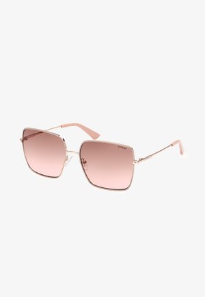 Quadratische Sonnenbrillen mit verlaufenden pinken Gläsern, metallic rose-gold Rahmen und hellpinkem Bügel. Mit dem Markennamen "GUESS" an der Seite.