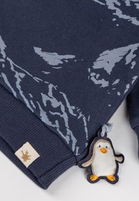 Felpa blu navy con motivo montano grigio chiaro, polsini a coste e un charm a forma di pinguino attaccato, realizzata in un tessuto morbido.