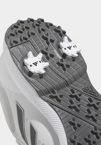 Vit sportskosula med intrikata grå gummimönster och två vita avtagbara spikar. Inkluderar Adidas-logotyp.