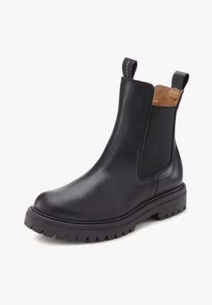 Botte Chelsea en cuir noir avec semelle épaisse, panneaux latéraux élastiques et languettes pour tirer à l'avant et à l'arrière, montrant une partie de l'intérieur en cuir marron clair.