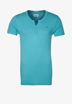 Turkusowa koszulka z krótkim rękawem, wykonana z miękkiego materiału, z dekoltem Henley i dwoma guzikami oraz małą naszywką z logo na klatce piersiowej.