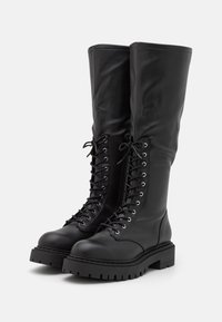 Bottes noires montantes en cuir lisse. Présentent un laçage frontal avec des œillets en métal, un bout arrondi et une semelle épaisse et texturée.