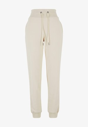 Beige joggebukser laget av mykt materiale, med elastisk midje med snorer og ribbestrikkede mansjetter ved ankler. Minimalistisk design.