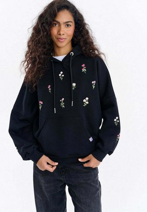 Czarna bluza z kapturem z kwiatowym haftem w kolorach różowym i białym. Posiada przednią kieszeń i sznurki, wykonana z miękkiego materiału o swobodnym kroju.