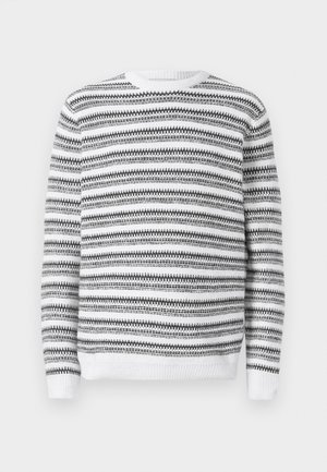 Pleteni pulover s okruglim izrezom, s crno-bijelim horizontalnim prugama i rebrastim manžetama i rubom. Meki tekstur.
