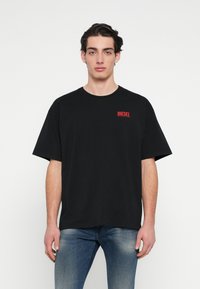 Mustast puuvillast T-särk lühikeste varrukatega, ümmarguse kaelusega ja vasakul rinnal punase "DIESEL" logoga. Sile tekstuur, mugav lõige.