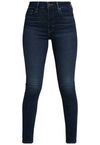 Tight jeans i mörkblå denim, med hög midja, klassisk femfickdesign och subtil blekning fram för djup.