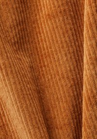 Texturiertem Stoff in warmem Orange, der vertikale Rippmuster aufweist. Weich und plüschig, hervorgehoben durch unterschiedliche Schattierungen in den Fasern.