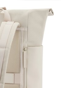 Beige roltop rugzak met een gladde buitenlaag, een mesh zijvak, ritsdetails en verstelbare schouderbanden.