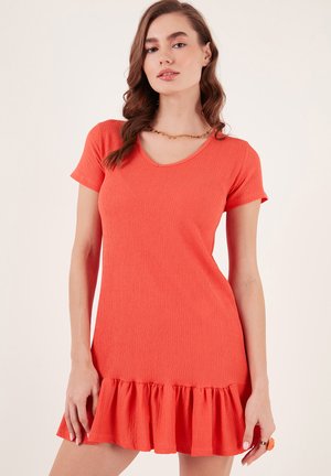 Short-sleeved dress in vibrant coral with a V-neck, textured fabric, and a flared ruffle hem. Stylish yet simple design.