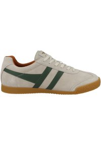 Sneaker in suede di un beige chiaro con strisce verdi. Presenta una suola in gomma testurizzata, un design con lacci e una fodera interna arancione.