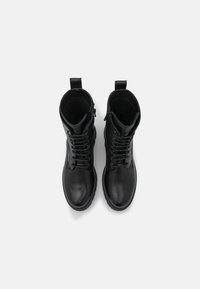 Czarne skórzane botki za kostkę o gładkiej fakturze, z przodem na sznurówki, zamkiem błyskawicznym po boku oraz pętelką na kołnierzu. Solidna konstrukcja z okrągłym noskiem.