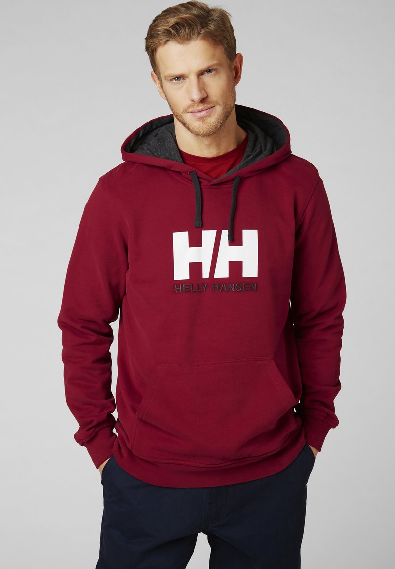 Bordová mikina s šedou podšívkou kapuce, zdobená velkým bílým logem "HH" a nápisem "HELLY HANSEN". Obsahuje přední kapsu a žebrované manžety.