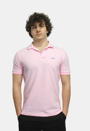 Polo in rosa chiaro con colletto a due bottoni, maniche corte, dettagli blu sul colletto e un piccolo logo sul lato sinistro del petto.