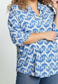 Blusa a fiori blu realizzata in tessuto leggero, con un taglio morbido, maniche a tre quarti e colletto.