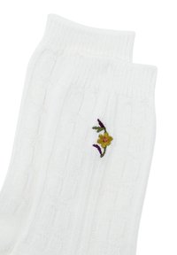 Calzini bianchi lavorati a maglia con una texture a coste e un design floreale ricamato in giallo, viola e verde su un lato.