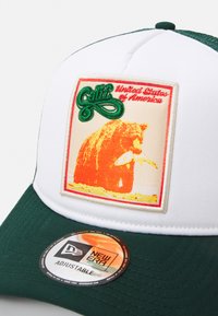 Căciulă ajustabilă verde și albă, cu un grafic al unui urs �și texte "Calif" și "Statele Unite ale Americii" brodate în portocaliu și verde vibrant.
