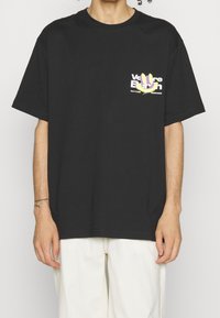 Zwart katoenen t-shirt met een grafische print aan de voorkant in paarse en gele accenten. Korte mouwen, losse pasvorm en geribbelde halslijn.